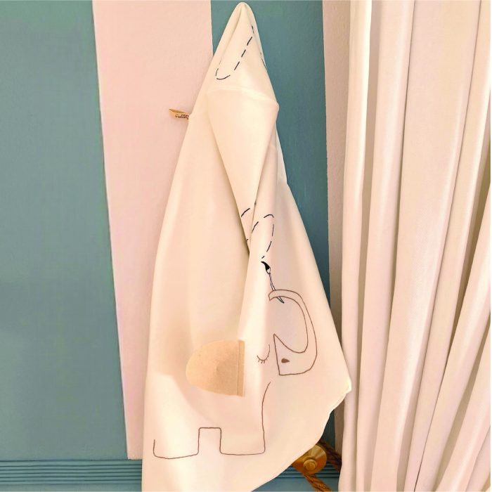 Hooded baby towel with embroidered elephant hanging in a nursery
